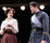 Beatrice holds a letter and looks amusingly at Benedick in uniform, who looks pained at the revelation in the letter