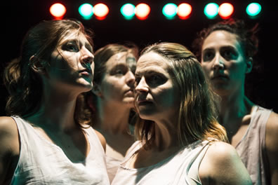 The four dancers together, facing right, right, left, and forward, with a row of green and red spotlights across the top of the photo