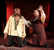 Othello and Iago kneeling, Iago with one hand raise, the other on Othello's shoulder